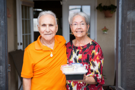 Meals on Wheels volunteer and client holding meal